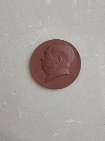 不多见的上世纪五六十年代毛泽东主席头像宜兴紫砂片像章。宜兴紫砂的毛主席半身或全身站座类像较为常见，而这类可以穿线挂于胸前的紫砂片像非常少见，穿线孔详见图四和五。形象丰满，砂质柔润可手，工艺较精。瑕疵:鼻上前方一处短约8毫米的天然窑线，脑后边沿两处肉眼不易识别的浅表飞皮，侧看右眼角处一处微跳砂孔，正面看不到，均详见图片。 尺寸:直径5.9公分，厚0.5公分，重35克。