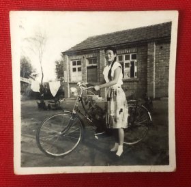 穿裙子的长辫子美女推着自行车在旧屋前留影老照片