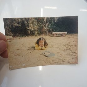老照片–小女孩趴在公园草坪上留影（太阳帽在旁边）