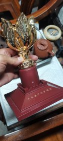 永远盛开的紫荆花鎏金摆件！14.5x14.5x21厘米，重2.9斤。金色花朵造型精美，底座酒红色，整体完整！ 底座刻有"永远盛开的紫荆花"字样，寓意美好。花朵造型立体，光泽度好，适合家居装饰或收藏。
