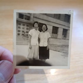 老照片-两名女子在室外合影 身后建筑清晰可见（二人穿裙子，开怀大笑）