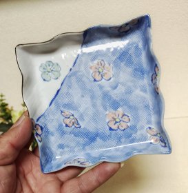 日本陶艺家中岛文山（人间国宝）本手作手捻青花染付小皿。全手工制作，先在网布上赶泥片，印上笼布的肌理，手捏成型，然后手绘釉下青花图案，高温成瓷后又手绘釉上图案点缀，底款戳记“文山”，成瓷后的小皿又薄又坚，形成了文山的特定风格。 直径12厘米，高2厘米。满58包邮偏远地区邮费自付