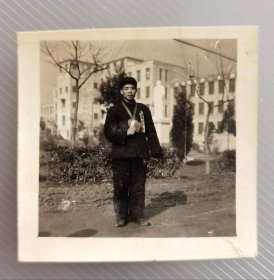 60年代安徽省先进生产者代表胸挂代表证、手握红宝书、脖戴塑料毛主席大像章留影，背有毛主席巨型雕像和时代标语