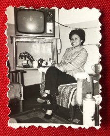 70年代美女坐在屋内沙发上（旁边摆着黑白电视机、茶杯、暖水瓶）留影特色老照片