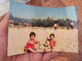 照片：80年代青岛第三海水浴场（八大关海水浴场）花石楼清晰可见，最关键的是两个小孩拿着女士香槟在喝。