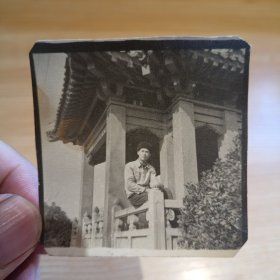 老照片-五十年代帅气青年坐在景区护栏上留影（戴帽子）