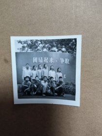 60年代黑白老照片一张 年轻人合照，背后有 团结起来争取更大的胜利 字样