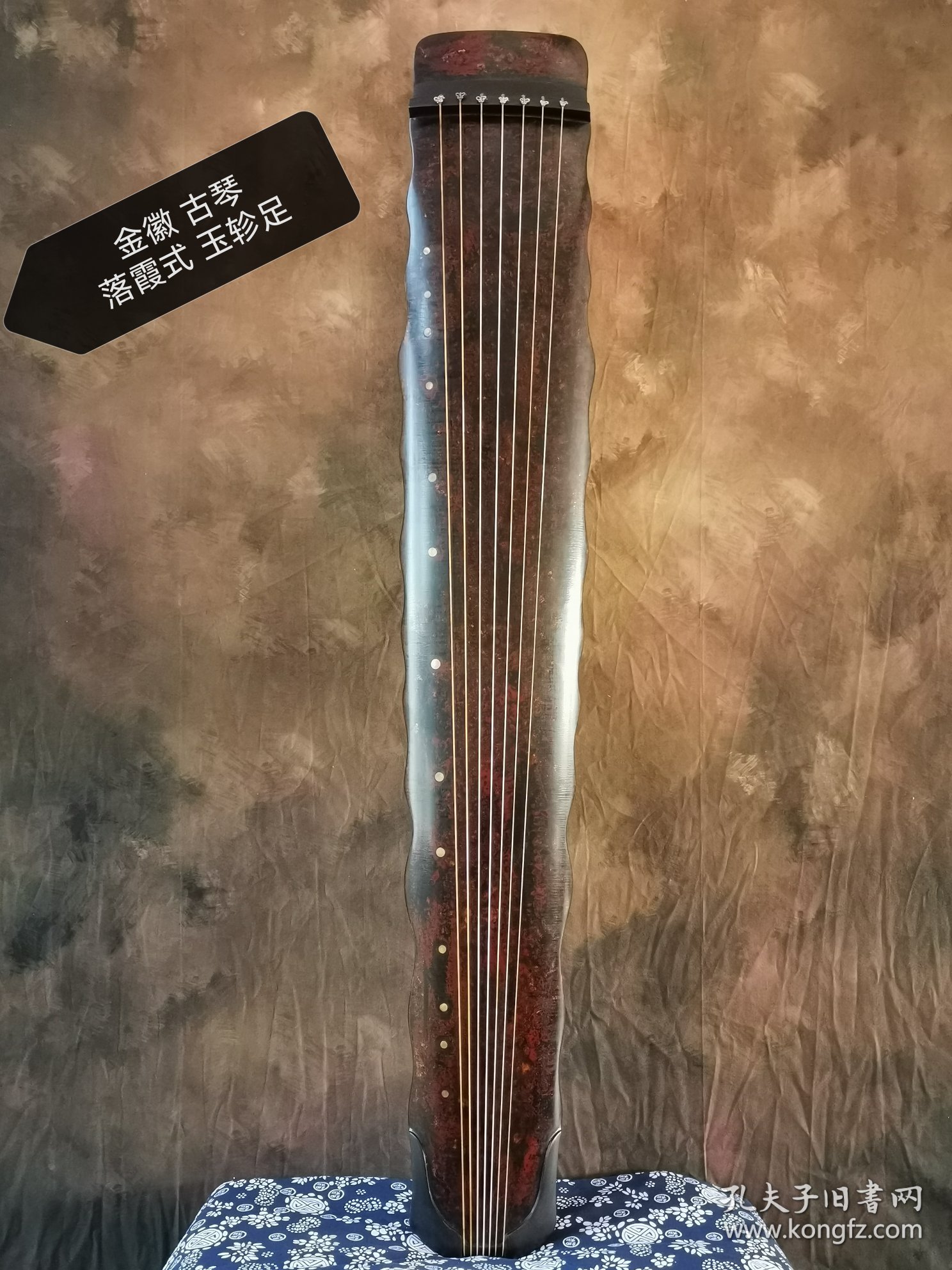 【金徽】落霞式 玉轸足 造型简洁朴素，声音清雅纯正。桐木制，轮廓线条挺拔有力，岳尾以紫檀制。琴面髹犀皮色漆，漆层致密，琴底髹暖栗色漆与深褐色漆。规整雅致，制作精良。金徽星罗井然，木轸如月华，精巧雅致。长方形龙池凤沼，龙池上刻 金徽二字，填有金痕，其音清朗松透，古朴内敛，实为存世古琴的可圈可点之作。