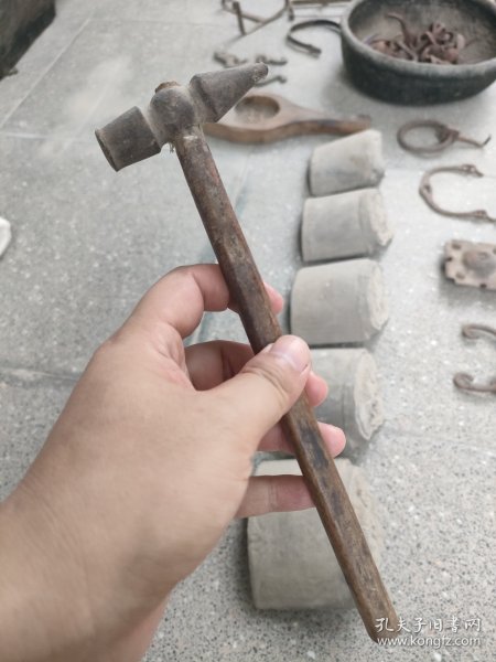出一把银匠古董锤子，具有复古的韵味和历史感。锤头部分由金属制成，表面略显磨损，颜色呈深褐色，手柄部分为木制，结实耐用。此锤子适合收藏或作为道具使用，可增添家居的艺术氛围。