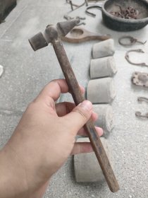 出一把银匠古董锤子，具有复古的韵味和历史感。锤头部分由金属制成，表面略显磨损，颜色呈深褐色，手柄部分为木制，结实耐用。此锤子适合收藏或作为道具使用，可增添家居的艺术氛围。