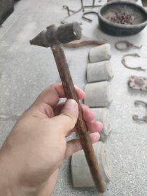出一把银匠古董锤子，具有复古的韵味和历史感。锤头部分由金属制成，表面略显磨损，颜色呈深褐色，手柄部分为木制，结实耐用。此锤子适合收藏或作为道具使用，可增添家居的艺术氛围。