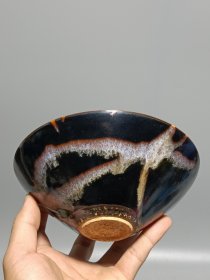 宋代吉州窑洒釉斗笠碗，窑变釉色，黑釉底色配红褐斑纹，釉面自然窑变，线条流畅。碗型规整，胎质细腻，底部干练，整体保存不错，无明显磕碰，品相以图为准。尺寸：直径15.6cm，高5.4cm。适合收藏或茶道使用。