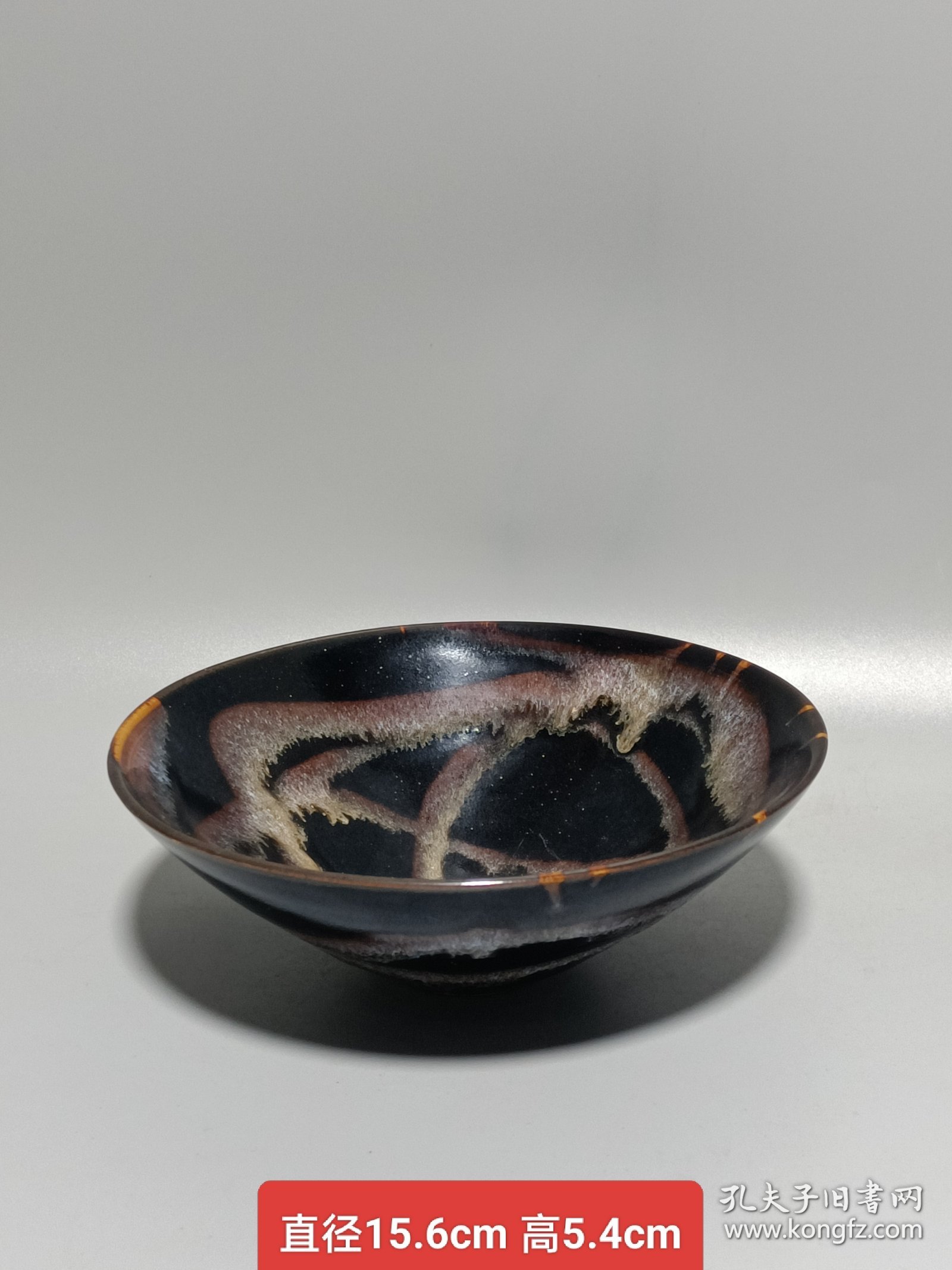 宋代吉州窑洒釉斗笠碗，窑变釉色，黑釉底色配红褐斑纹，釉面自然窑变，线条流畅。碗型规整，胎质细腻，底部干练，整体保存不错，无明显磕碰，品相以图为准。尺寸：直径15.6cm，高5.4cm。适合收藏或茶道使用。