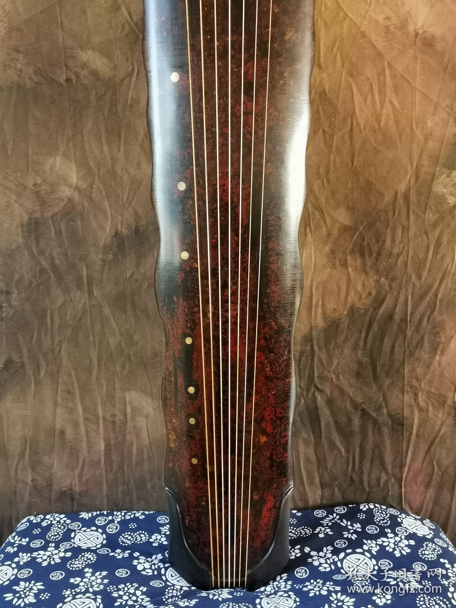 【金徽】落霞式 玉轸足 造型简洁朴素，声音清雅纯正。桐木制，轮廓线条挺拔有力，岳尾以紫檀制。琴面髹犀皮色漆，漆层致密，琴底髹暖栗色漆与深褐色漆。规整雅致，制作精良。金徽星罗井然，木轸如月华，精巧雅致。长方形龙池凤沼，龙池上刻 金徽二字，填有金痕，其音清朗松透，古朴内敛，实为存世古琴的可圈可点之作。