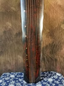 【金徽】落霞式 玉轸足 造型简洁朴素，声音清雅纯正。桐木制，轮廓线条挺拔有力，岳尾以紫檀制。琴面髹犀皮色漆，漆层致密，琴底髹暖栗色漆与深褐色漆。规整雅致，制作精良。金徽星罗井然，木轸如月华，精巧雅致。长方形龙池凤沼，龙池上刻 金徽二字，填有金痕，其音清朗松透，古朴内敛，实为存世古琴的可圈可点之作。