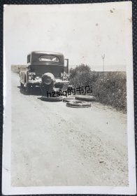 民国时期马路旁停靠的小轿车和换轮胎场景，老照片内容少见，较为难得
