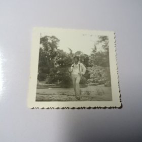 老照片–帅气青年站在景区池塘边留影（身后假山和树木清晰可见）