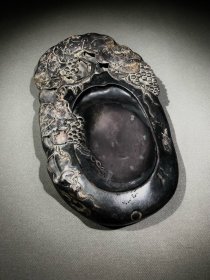屠倬款，多子多福，子孙满堂，端砚，巧妙结合天然石皮雕刻葡萄，寓意多子多福，子孙满堂。雕功精细灵动逼真，包浆自然浑厚，天然火捺、蕉叶白、石眼等名贵石品。砚长26.5厘米，宽15.8厘米，厚3.6厘米。 砚背有一天然石眼，石眼上方刻诗文，落款：屠倬。