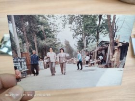 彩色照片。1990年街道两侧有卖早点的，有炒菜，炒面，饺子，日供应有大铝锅，有凉棚搭的小吃部。两个穿西服的女干部，在街道上，路过摄影师抓拍镜头。