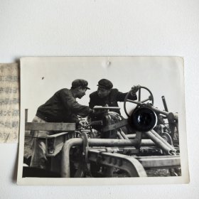 1956年全国人大代表，『毛泽东号』机车司机长的李勇。以及『大林式拖拉机包车组』组长赵未在拖拉机上面亲切交谈，并互相了解工作和生活情况。新中国老照片。 照片净尺幅：11*8.2cm