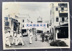 【广州旧影】1939年7月7日 卢沟桥事变两周年汪伪政府“兴亚纪念日”当天广州十七甫路花牌楼前招摇过市的汪伪“广东全省保安司令部”及“国民政府军事委员会”游行队伍 原版老照片一枚（身穿白色军装的队伍为“广东全省保安司令部”，其后汪伪将领带领的队伍中高举“国民政府 军事委员会委员长* 广东各界庆祝兴亚七七纪念大巡行”字样条幅，路旁建筑上可见“天生装饰图案公司 各种印刷制本文房具制图用品”字样广告。）