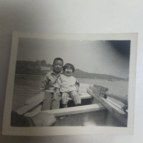 两个小孩儿坐在船上，在景区合影留念照片