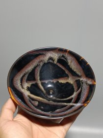 宋代吉州窑洒釉斗笠碗，窑变釉色，黑釉底色配红褐斑纹，釉面自然窑变，线条流畅。碗型规整，胎质细腻，底部干练，整体保存不错，无明显磕碰，品相以图为准。尺寸：直径15.6cm，高5.4cm。适合收藏或茶道使用。