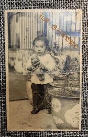 民国老照片抱着洋娃娃站在古董花盆前扎冲天辫的小孩
