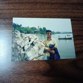 老照片–戴眼镜男子站在湖边景观石旁留影（身后游船和白塔清晰可见）