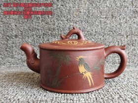 近代宜兴蜀山陶业生产合作社出品的紫砂壶，高9厘米，长16厘米，容量约280毫升 。壶身呈古朴棕红色，造型别致，壶钮、壶嘴与壶把皆作精巧仿生设计。壶身绘有栩栩如生的鸟栖竹枝图，壶盖饰以精致花纹，将传统工艺与自然意趣完美融合，既承载着时代印记，又具实用与艺术价值，是紫砂文化中一抹独特的亮色。
