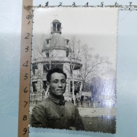 老照片：一位男士在武汉中山公园留影、背景是：“张公亭”廊柱上悬挂“伟大的中国共产党万岁、世界人民大团结万岁”布标、尺寸：6×8.5cm