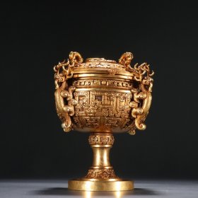 战汉时期 铸铜胎鎏金四龙豆 规格：高16cm 口径10.5cm 重837g 此豆盖中央置圆形捉手，周围饰夔龙纹。子母口，圆鼓腹，四龙作耳，构思巧妙。该豆尤其注重耳部装饰，上饰卷云纹、鳞纹，浮雕感甚强。该豆造型规整精美，纹饰生动细腻，通体鎏金，宝光泽泽，具有极高的艺术性和收藏价值。