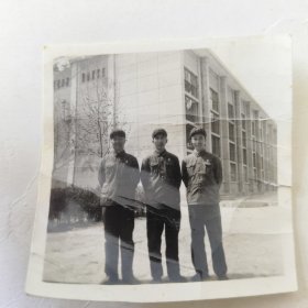 三位带着军帽的战士在楼前合影留念照片