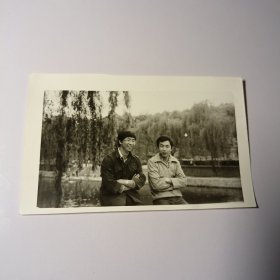 老照片–两名青年坐在景区垂柳旁留影（2）