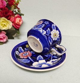 日本陶瓷中最显赫的品牌之一Nikko。创立于1908年，200年前英国创制了骨瓷。而Nikko则是将骨瓷中的骨粉含量提高到50%，研制出最高素质的骨瓷产品。此套早期的NiKKo骨瓷杯碟不仅质地优良，而且将日本文化中独特的精致韵味融入了其设计之中，深海蓝加上手绘的写意牡丹。使其色彩鲜明，釉面光泽柔和。昭和早期产品，略有开片。杯口径9.5厘米，高6.5厘米，碟直径16厘米，高2.5厘米。