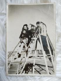 民国时期：烫发美女抱着小孩坐在云梯上合影留念老照片