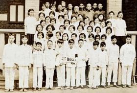 1935年 小学毕业生与老师合影照一枚（前排男生手持带“1935”等字样校旗，中间四排为女学生，最后一排为学校教师和校董。）