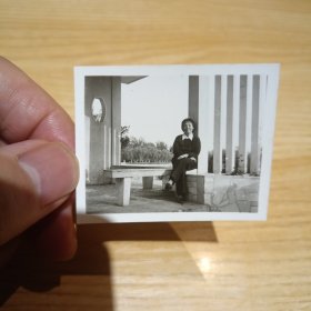 老照片–女子坐在景区留影（左侧漏窗和树木清晰可见）