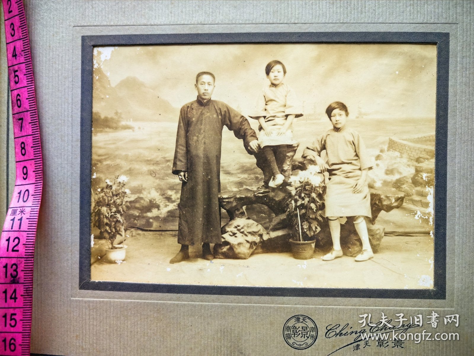 民国时期一家三口合影，小美女坐在假山上。天津景彰照相馆。底板考究精美。