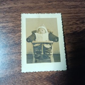 老照片–小宝宝坐在婴儿椅里留影（戴尖顶帽）