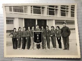 武汉地质学院（今中国地质大学武汉）1981年教工女子篮球赛冠军队合影，武汉地质学院工会颁发奖旗。中国地质大学教授彭文能（照片右三）保存。比赛于1981年12月20日颁奖
