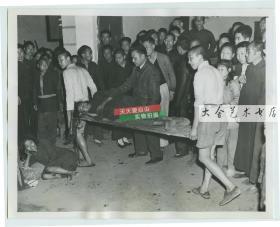 1946年中国内战期间湖南大饥荒，在衡阳有妇女在街头饿晕，被人用门板抬走救治。照片是当地教堂拍摄的。