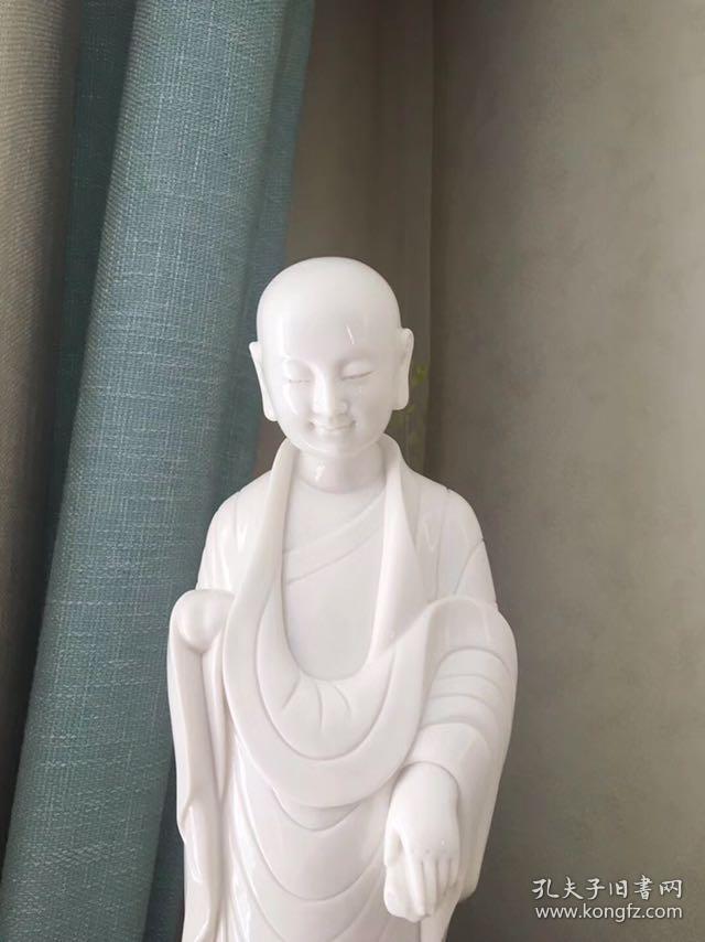 白瓷微笑小佛陀，家居装饰佳品，带包装 此艺术品为白瓷，瓷雕表面白洁如玉，衬托以小沙弥佛性的微笑，佛陀面部刻画俊朗，面部轮廓甜美，俊雅，展现东方式的迷人微笑，渡人向善，让欣赏者心灵受到净化变得安静纯净。尺寸高约35cm，肩宽约11cm。