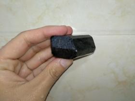 煤精石或黑玛瑙料一块，有玻璃光泽，周身切面九面，一端切面三面，另一段保留原石皮。
