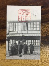 大清国安东县（辽宁丹东）胜武洋行明治42年（1909年）寄日本黑白照明信片一件、画面是一群人站在胜武洋行前，疑似该洋行全体员工。另有招牌：电灯柱广告，日本赤十字社，大同生命保险，照片上钤有一枚“恭贺新年”印章。 贴日本邮票1.5钱一枚、销安东县客邮局戳。具体请自查.（65#）