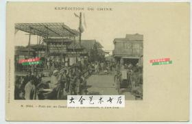 清末民初时期天津繁华的大街，街道景象可见牌楼前人头攒动，街上有拉人力车的车夫，老明信片一张。