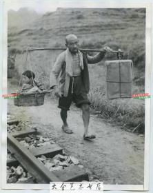 1944年日军侵华时期，一名中国父亲用扁担挑着自己的财产和孩子沿着铁路线行走躲避战乱老照片 （可能拍摄于湖南衡阳或常德一带）