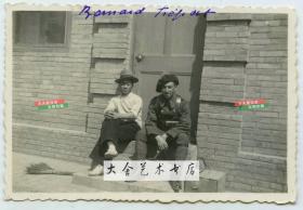 1937年在天津北洋机器局旧址现法国兵营中，一名法国士兵和一名年轻的中国男子坐在台阶上合影