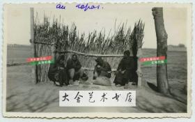 民国时期天津路边售卖枣子一类商品的小贩，路边搭有简陋地防风篱笆，供休息的人躲避冬季的寒风