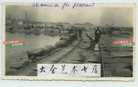 民国时期天津发大水冲毁了铁路浮桥老照片，路轨已经完全扭曲。远处可见大型工厂和烟囱